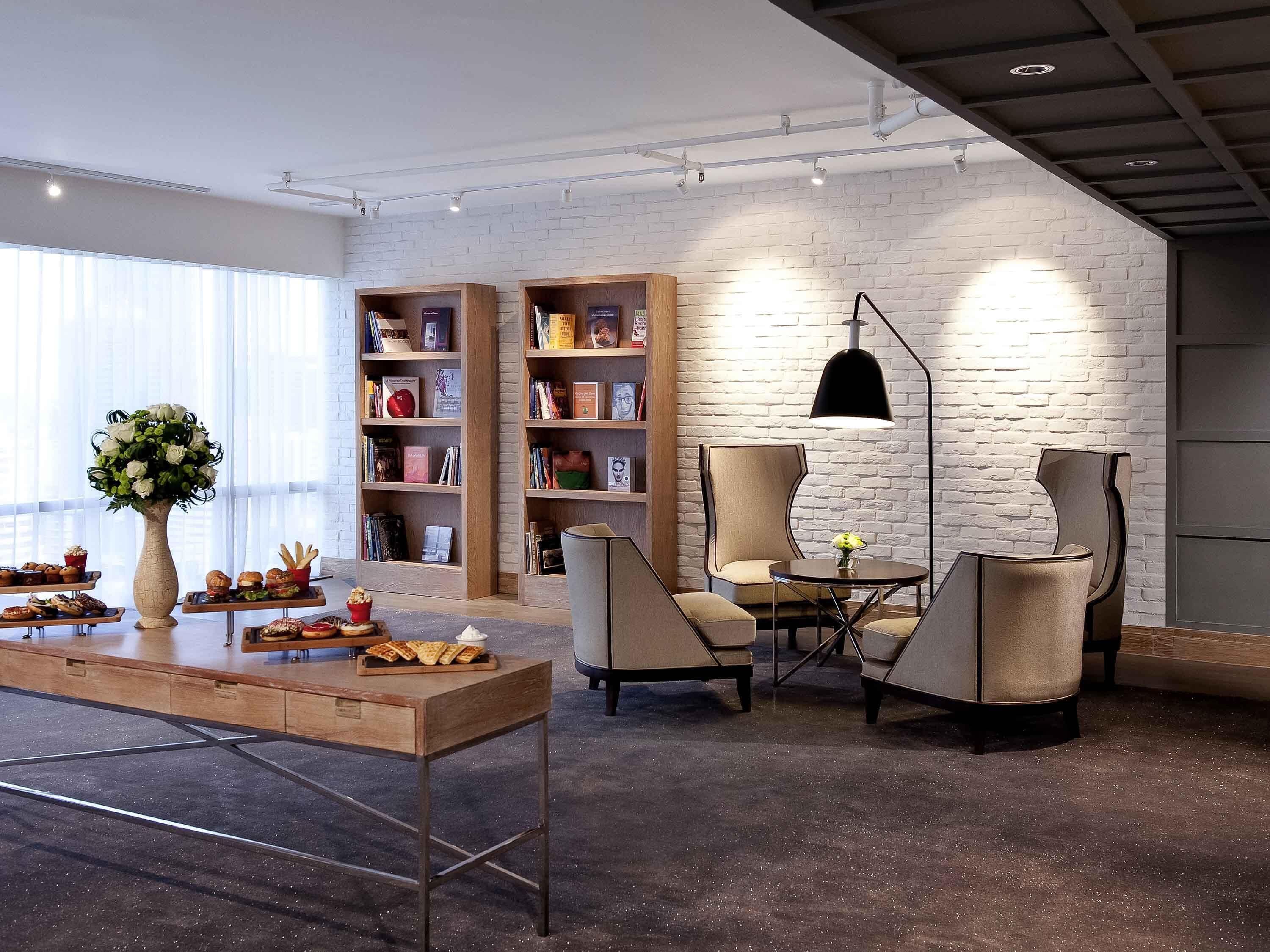A modern lounge area with a brick wall, wooden bookshelves, a round table, and two chairs.