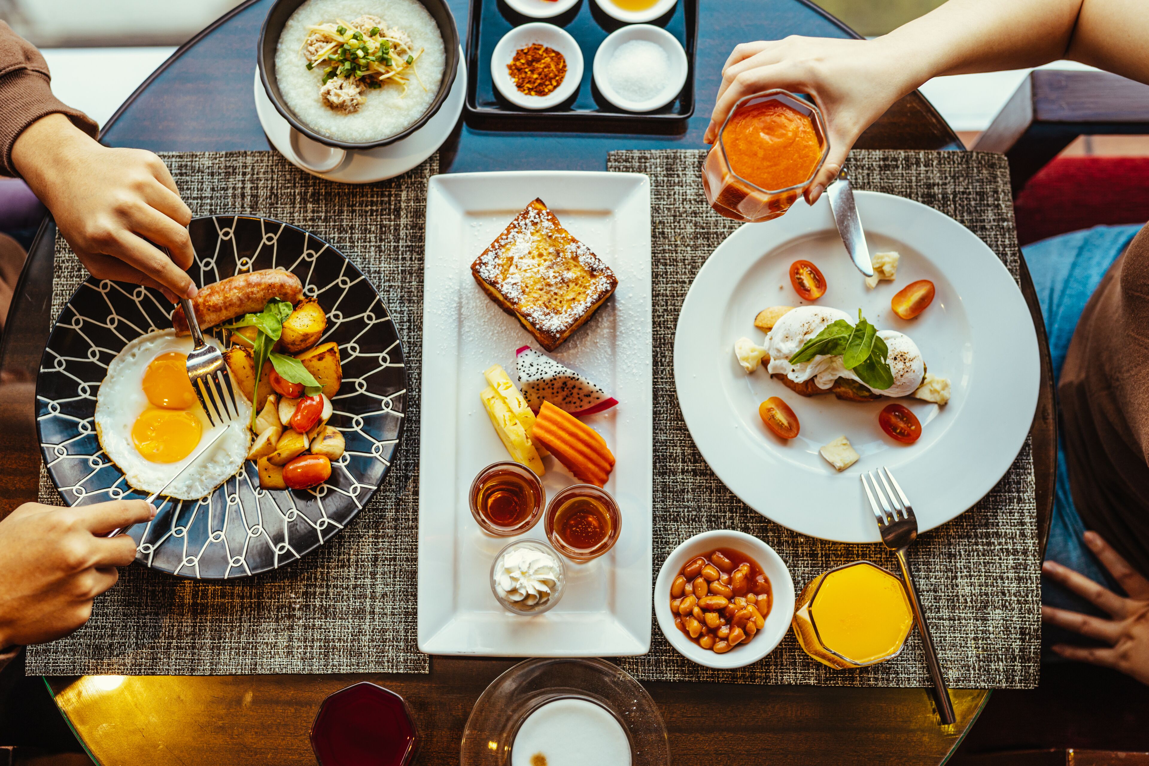 Een eettafel met diverse gerechten, waaronder eieren, toast en groenten.