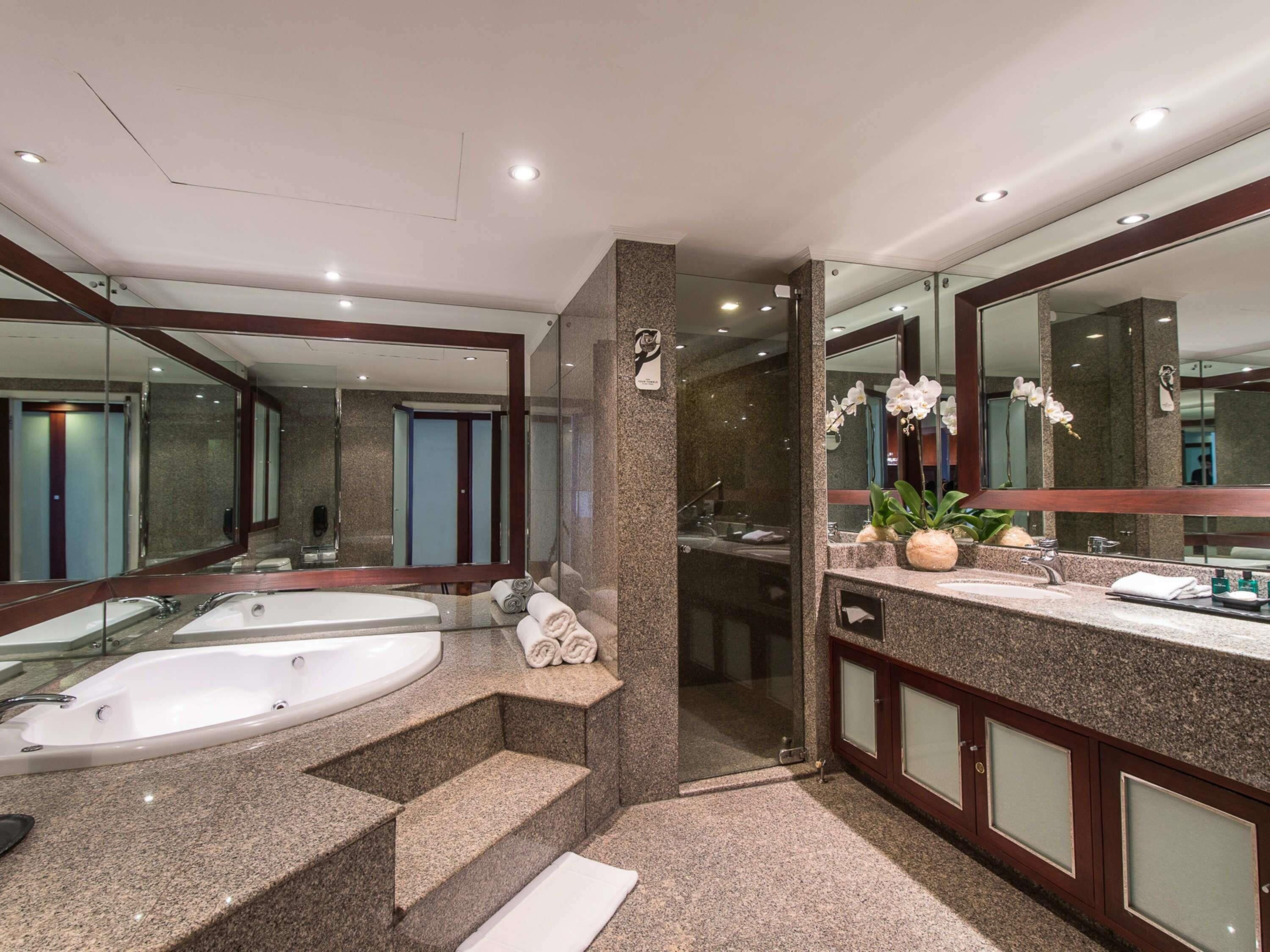 A modern bathroom with a large bathtub, a separate shower area, and a vanity with a mirror.