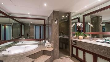 A modern bathroom with a large bathtub, a separate shower area, and a vanity with a mirror.