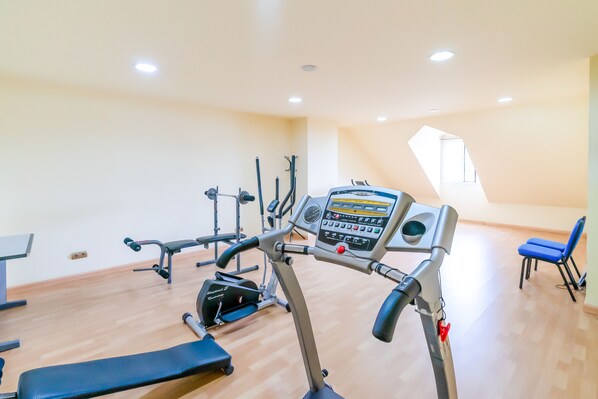 A gym with various exercise equipment, a bench, and a blue chair.
