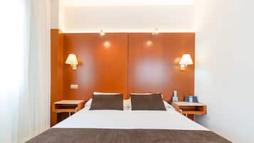 Una camera d'albergo moderna con un letto grande, due comodini e lampade a parete.