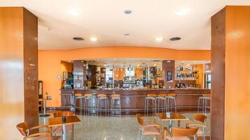 Zona de bar moderna con una barra curva, varios taburetes y una máquina de café.
