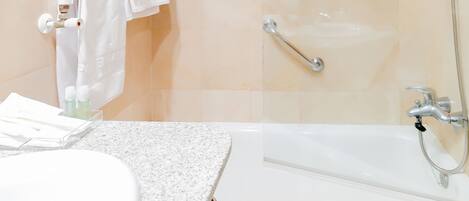 Un baño moderno con una bañera, una ducha con cerramiento de vidrio y un lavamanos blanco con encimera de granito.