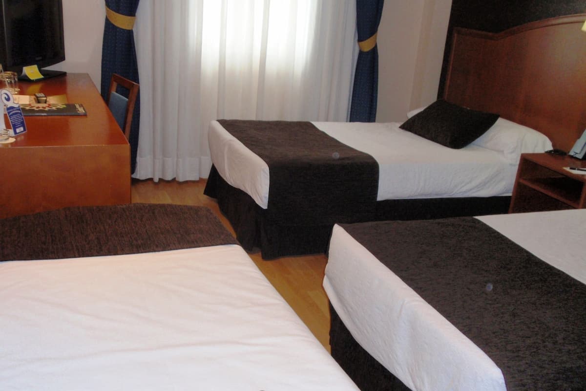 Una habitación de hotel con dos camas, un escritorio y un televisor.