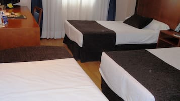 A hotel room with two beds, a desk, and a television.