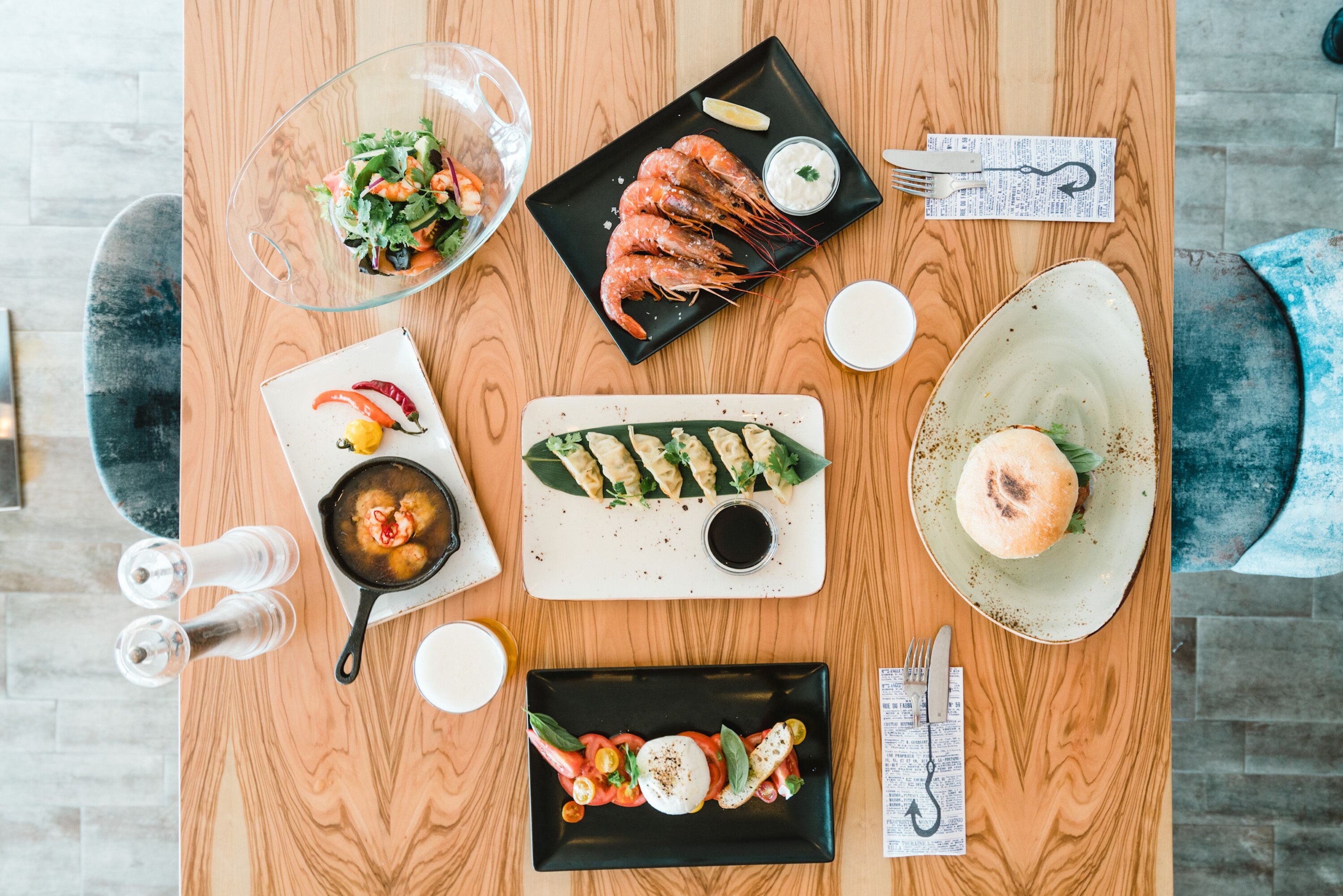 A wooden dining table with various dishes including shrimp, salad, and a plate of vegetables.