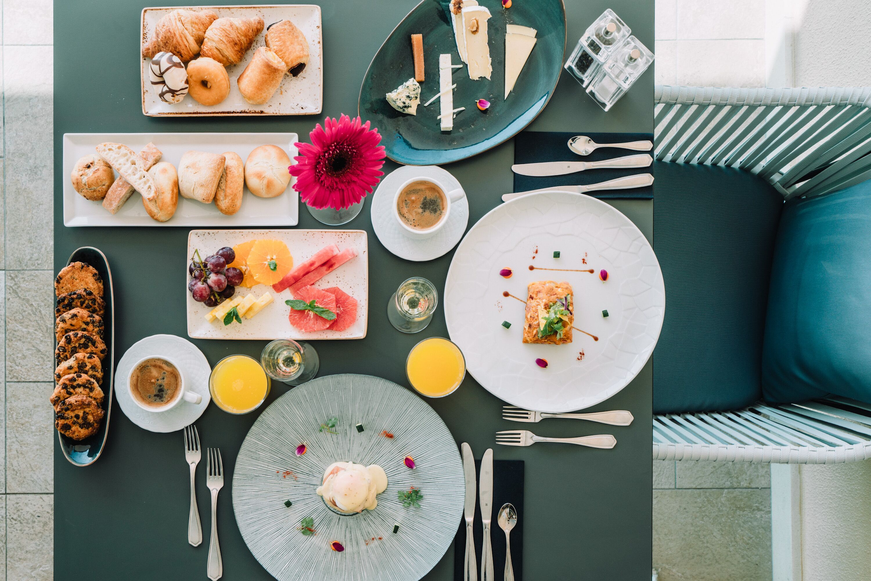 Morgenmad med croissanter, kager, frugt og drikkevarer på et bord.