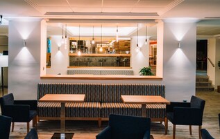 Un interior moderno con una zona de estar central, una barra y lámparas colgantes.