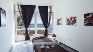 Un dormitorio con cama, una mesita y una ventana con cortinas.