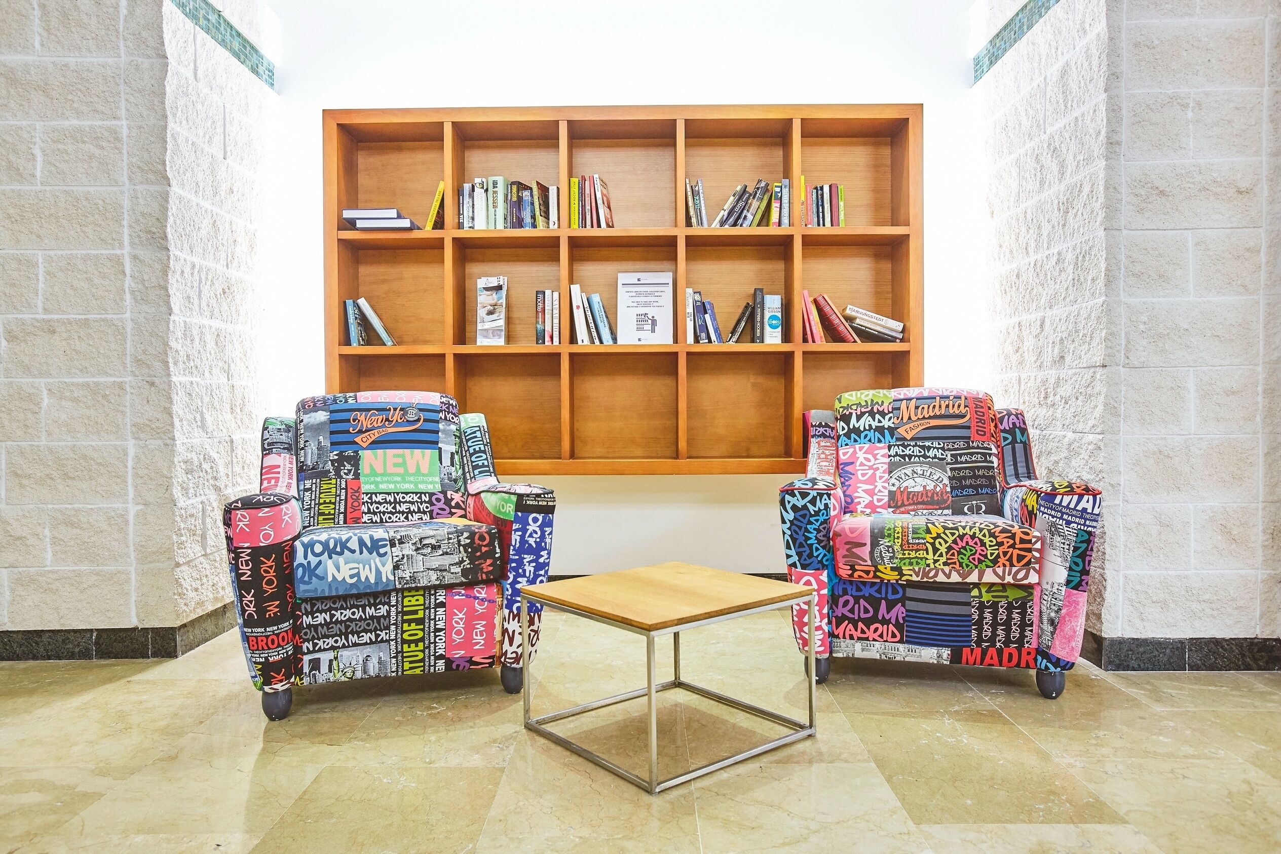 Une bibliothèque avec des étagères et deux chaises recouvertes d’autocollants colorés.