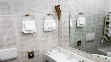 Et moderne badeværelse med hvid vask, spejl og toilet.