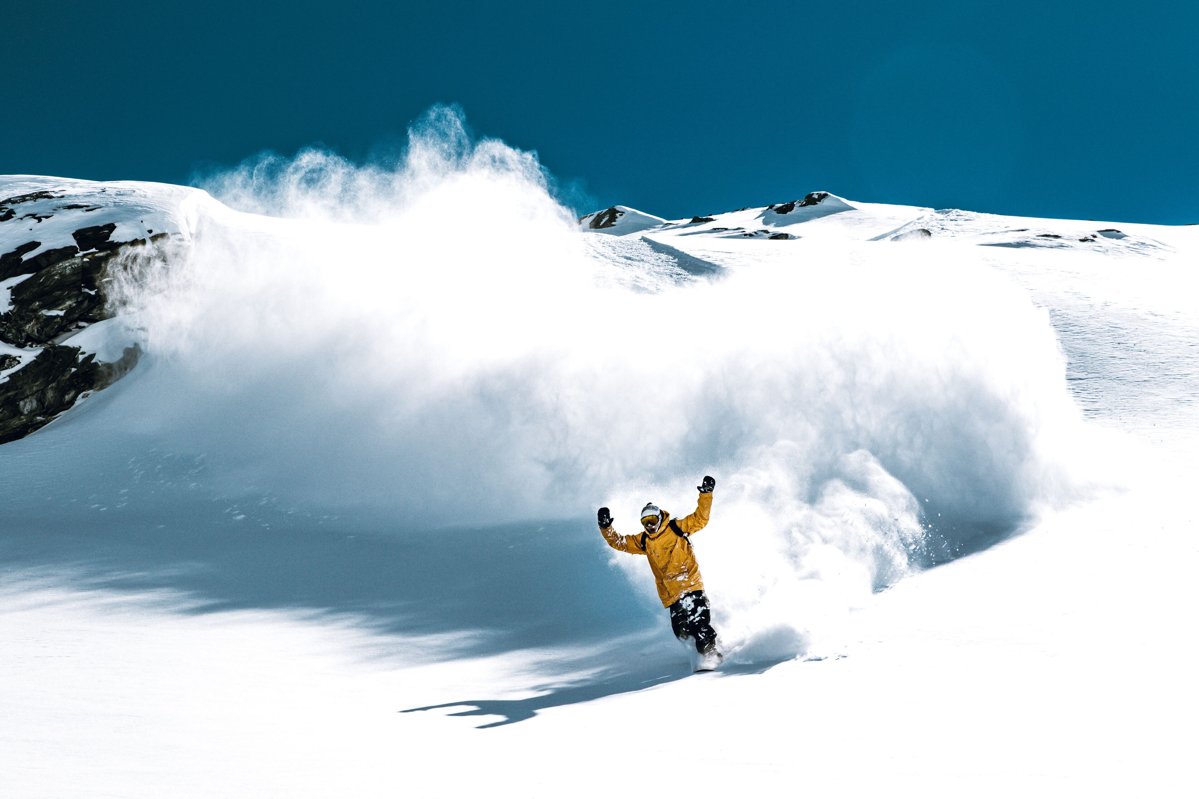 A snowboarder in a yellow jacket on a snowy mountain.