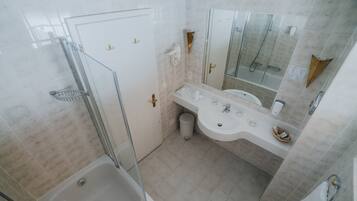 Un baño con ducha, bañera, lavabo y espejo.