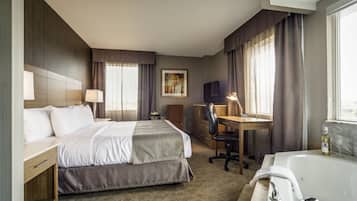 A hotel room with a bed, desk, chair, and a large bathtub.