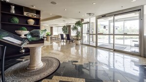 A modern lobby with a marble floor, a reception desk, and a seating area with chairs and a table. - Monte Carlo Inn Airport Suites (Mississauga)