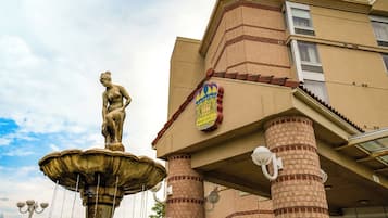 Un edificio con una fuente que presenta una estatua clásica, un escudo de armas y una escalera.