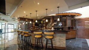 A bar area with a counter, stools, and a variety of bottles and glasses. - Monte Carlo Inn Airport Suites (Mississauga)