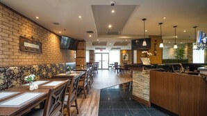 A restaurant with brick walls, wooden tables, and a tiled floor. - Monte Carlo Inn Airport Suites (Mississauga)