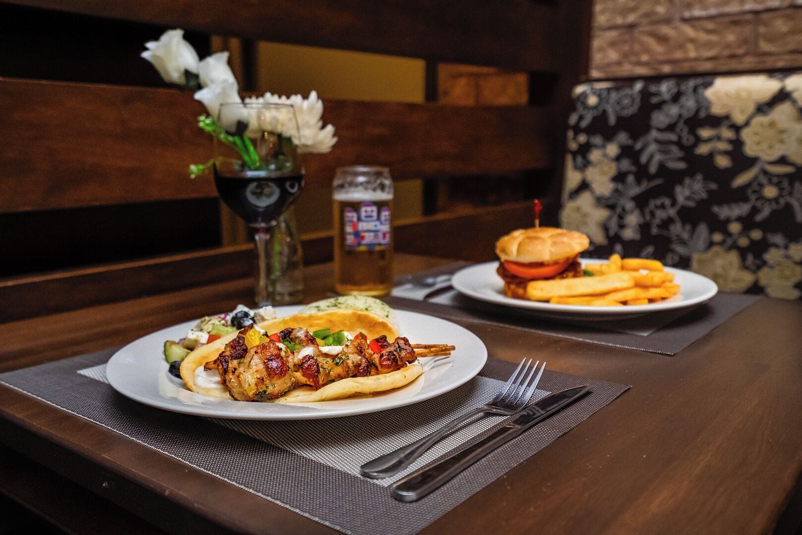 Een eettafel met een bord gegrilde kip en groenten, een hamburger en friet.