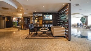 A lobby with a checkered floor, a seating area with a coffee table, and a vending/ice machine. - Monte Carlo Inn Airport Suites (Mississauga)