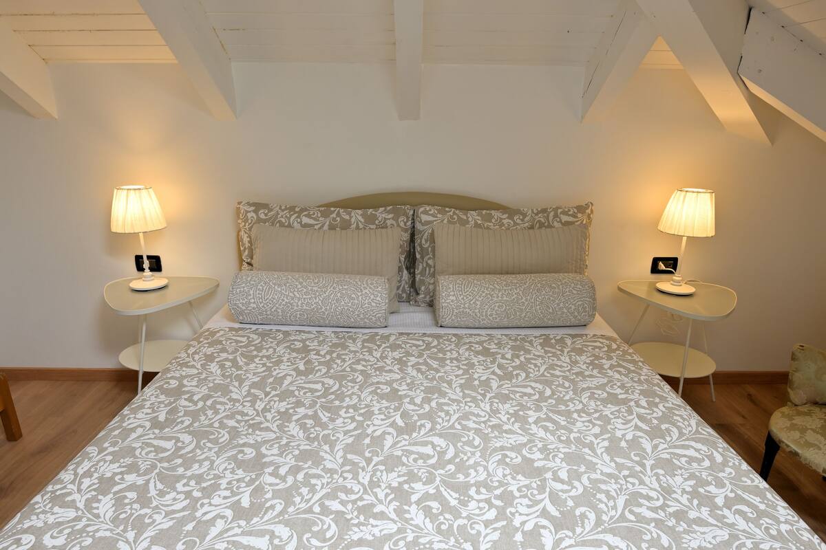 A bedroom with a large bed, two bedside tables with lamps, and a chair.