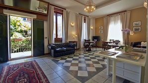 A living room with a checkered floor, a sofa, a dining table with chairs, and a chandelier. - Hotel Bagliori (Milan)
