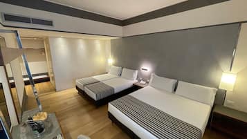 A hotel room with two beds, a desk with a lamp, a chair, and a small table with a remote control.