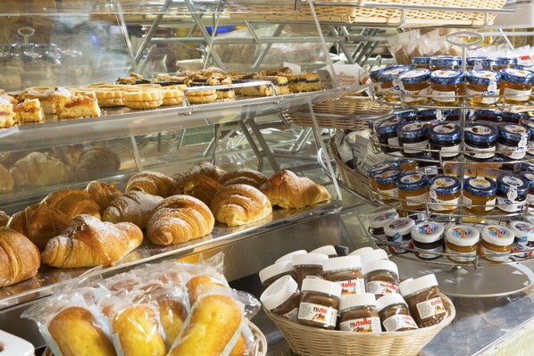 A bakery display with various pastries, croissants, and jars of Nutella.