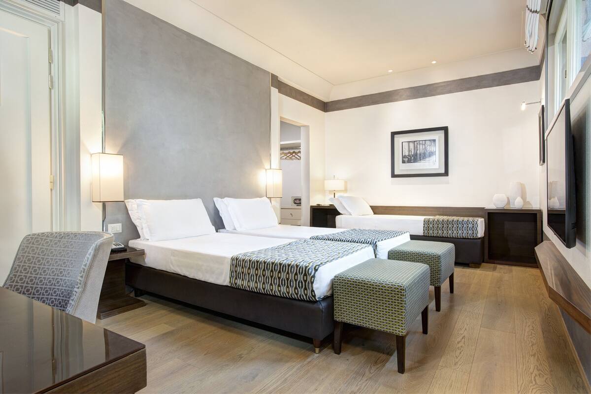 Une chambre d’hôtel moderne avec un grand lit, deux tables de chevet, un bureau et une télévision.