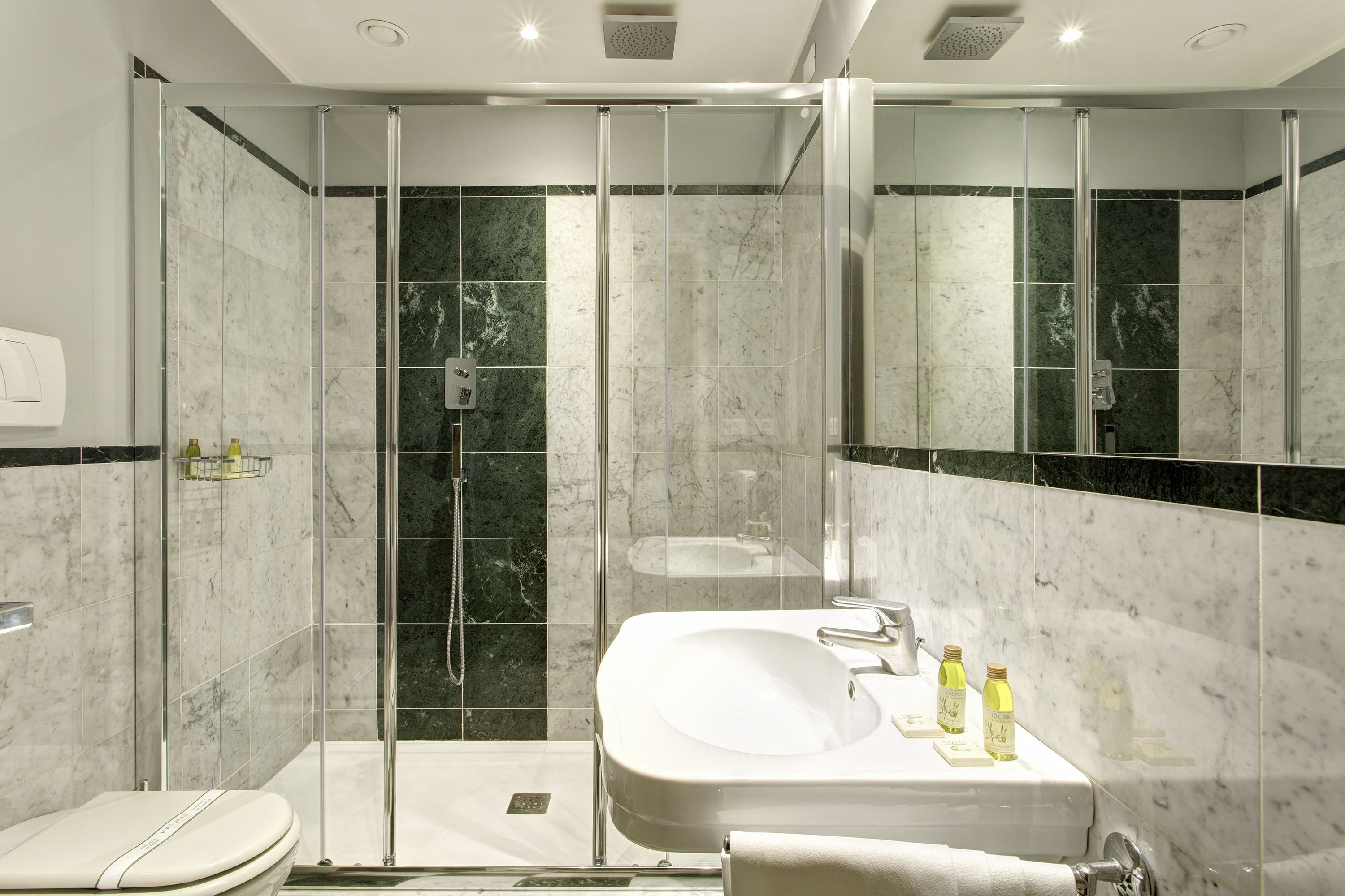 A modern bathroom with a glass-enclosed shower, a white sink, and a toilet.