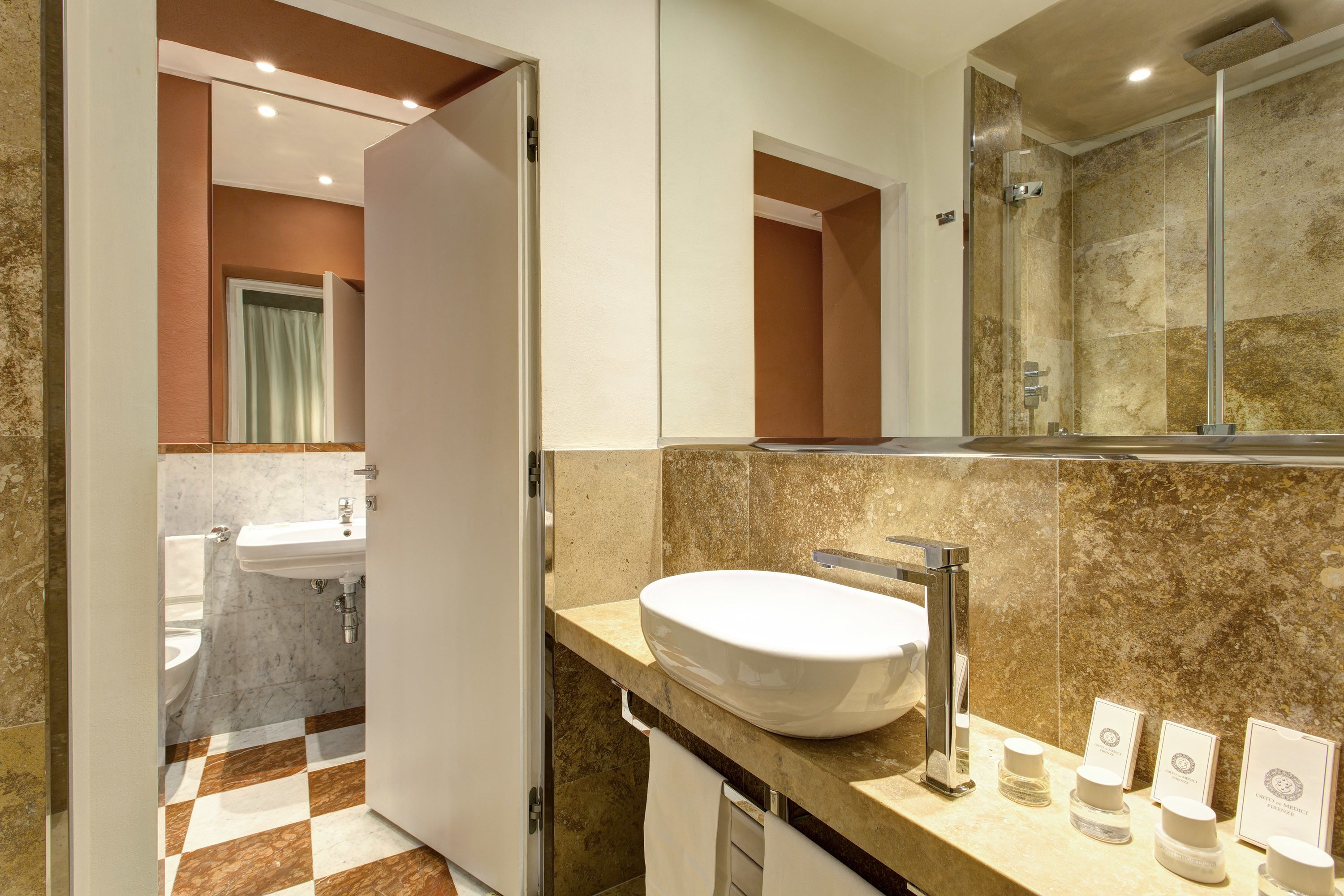 A modern bathroom with a large sink, a shower, and a mirror.