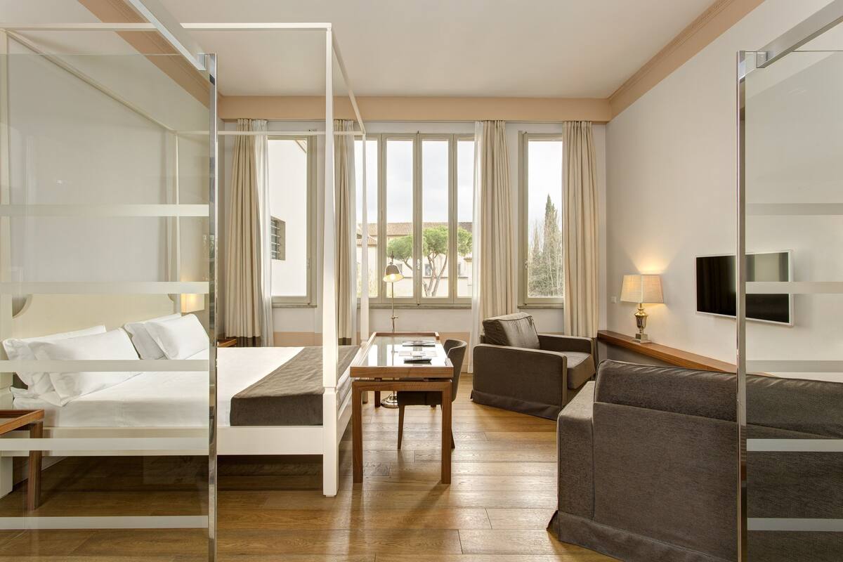 Une chambre d’hôtel avec un lit, un bureau, un canapé et une télévision.