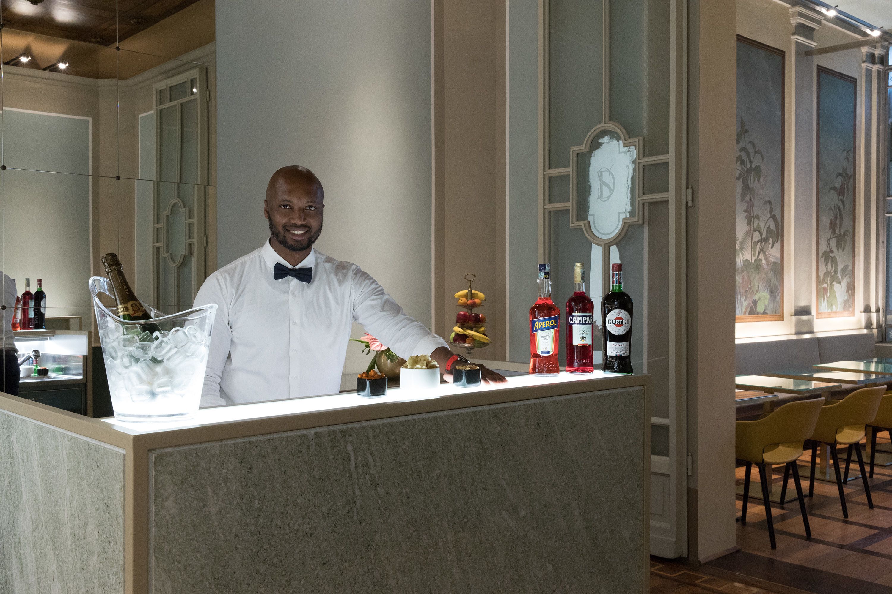 A bar area with a bartender, ice bucket, bottles, and a decorative mirror.