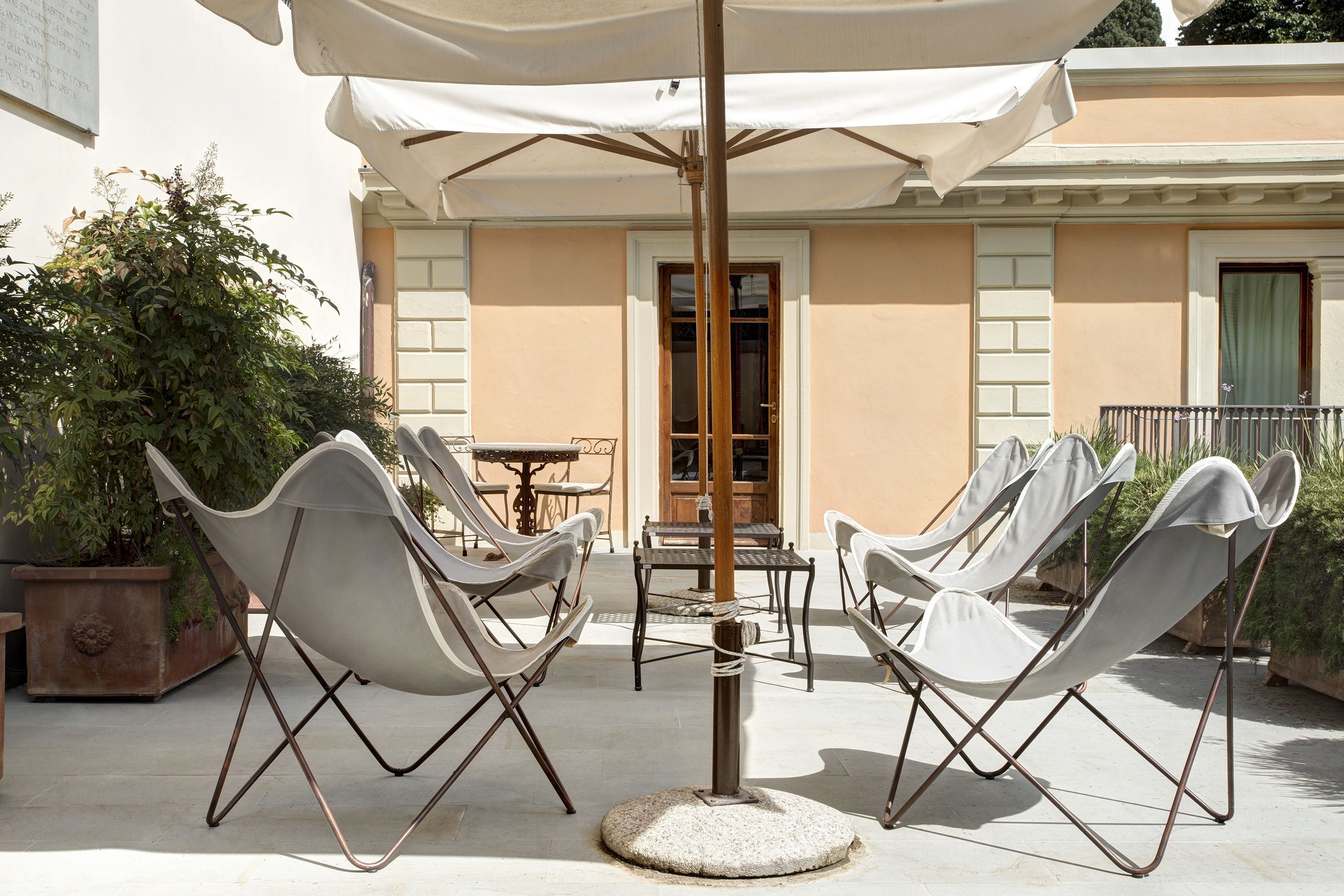 A patio with white folding chairs and a table under a large umbrella.