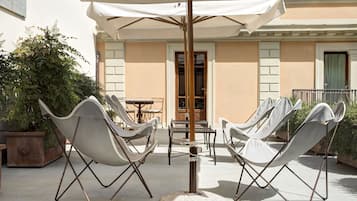 A patio with white folding chairs and a table under a large umbrella.