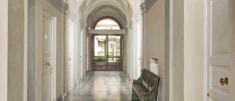 A corridor with arched ceilings, a checkered floor, and a bench.