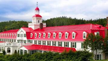 A large building with a red roof and white walls, featuring a bell tower and multiple windows.