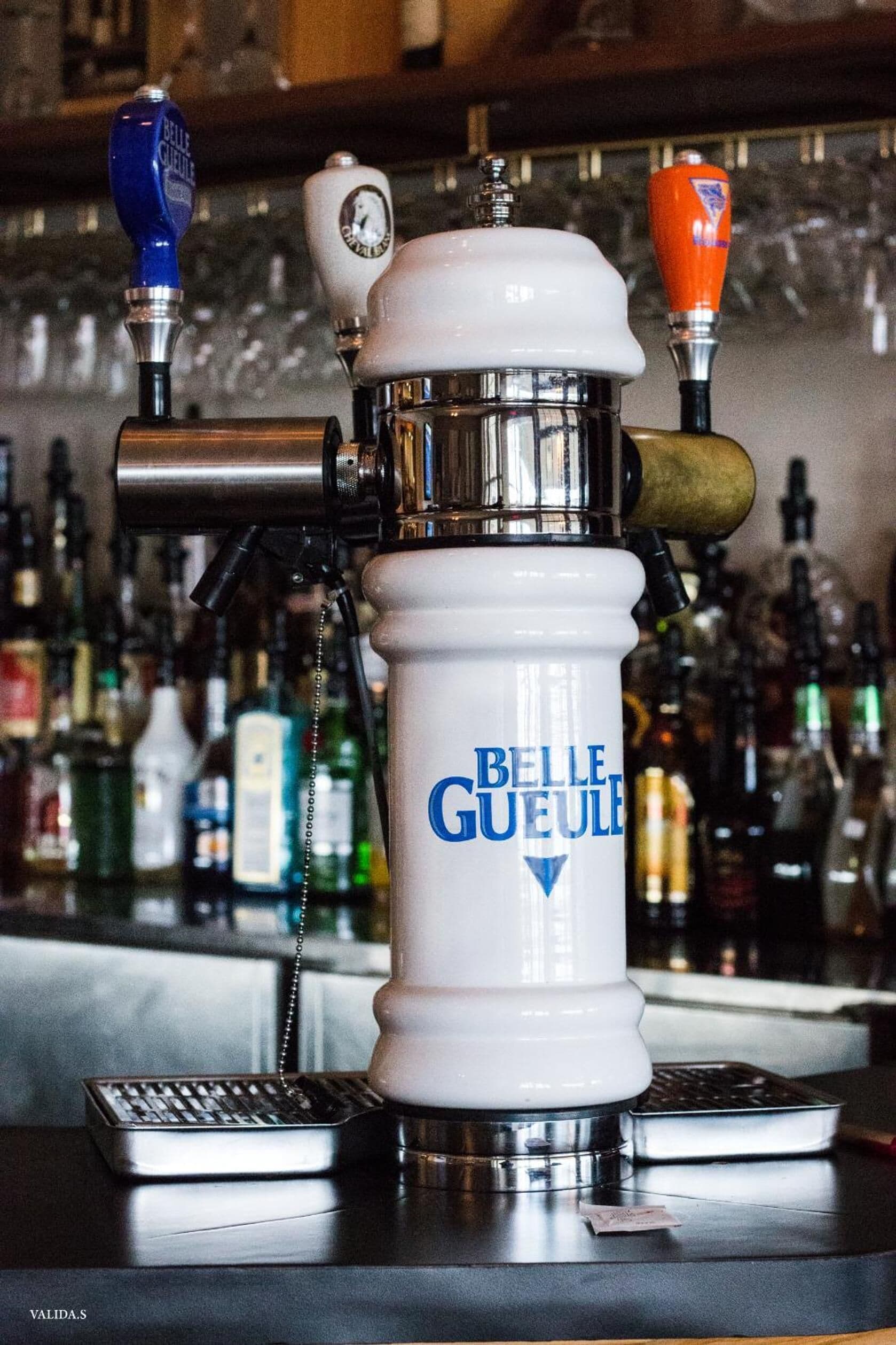A bar with a beer tap labeled "Belle Gueule" and various bottles in the background.