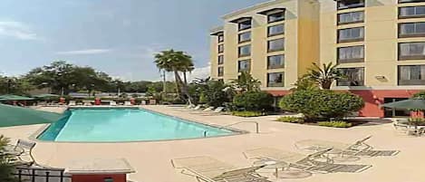 Ein Hotel mit Swimmingpool, Außenbereich und Palmen.