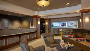 A modern lobby with a reception desk, seating area, and a large screen displaying content. - SpringHill Suites by Marriott Tampa Westshore Airport (Tampa)