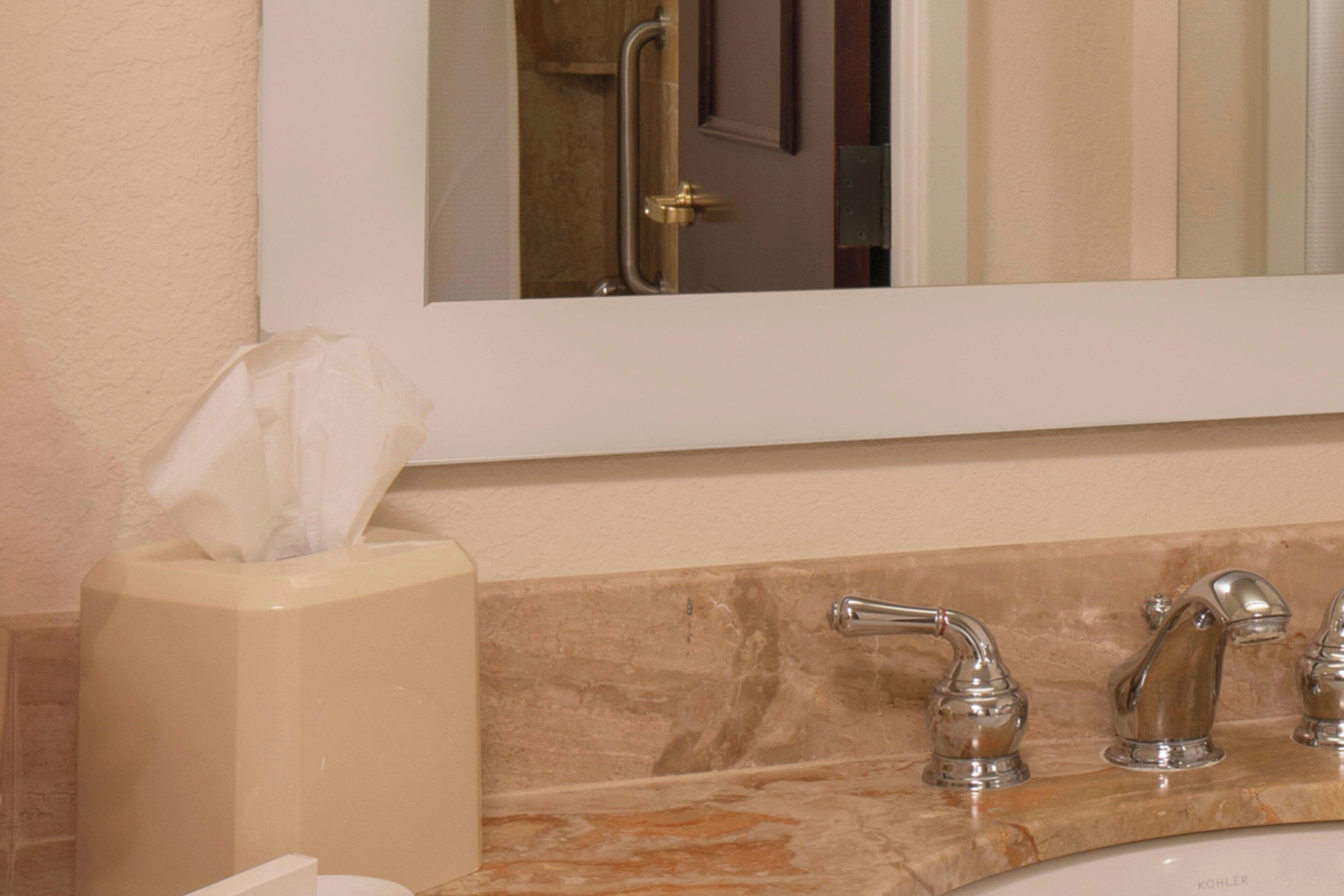 Une salle de bain avec un lavabo en marbre, un miroir et une boîte à mouchoirs.