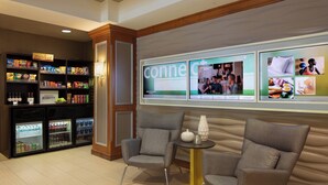 A hotel lobby with a kitchenette area, a seating area with armchairs, and a large wall display with the word "connect". - SpringHill Suites by Marriott Tampa Westshore Airport (Tampa)
