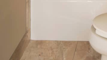 Un baño con una bañera blanca, un inodoro y piso de baldosas.