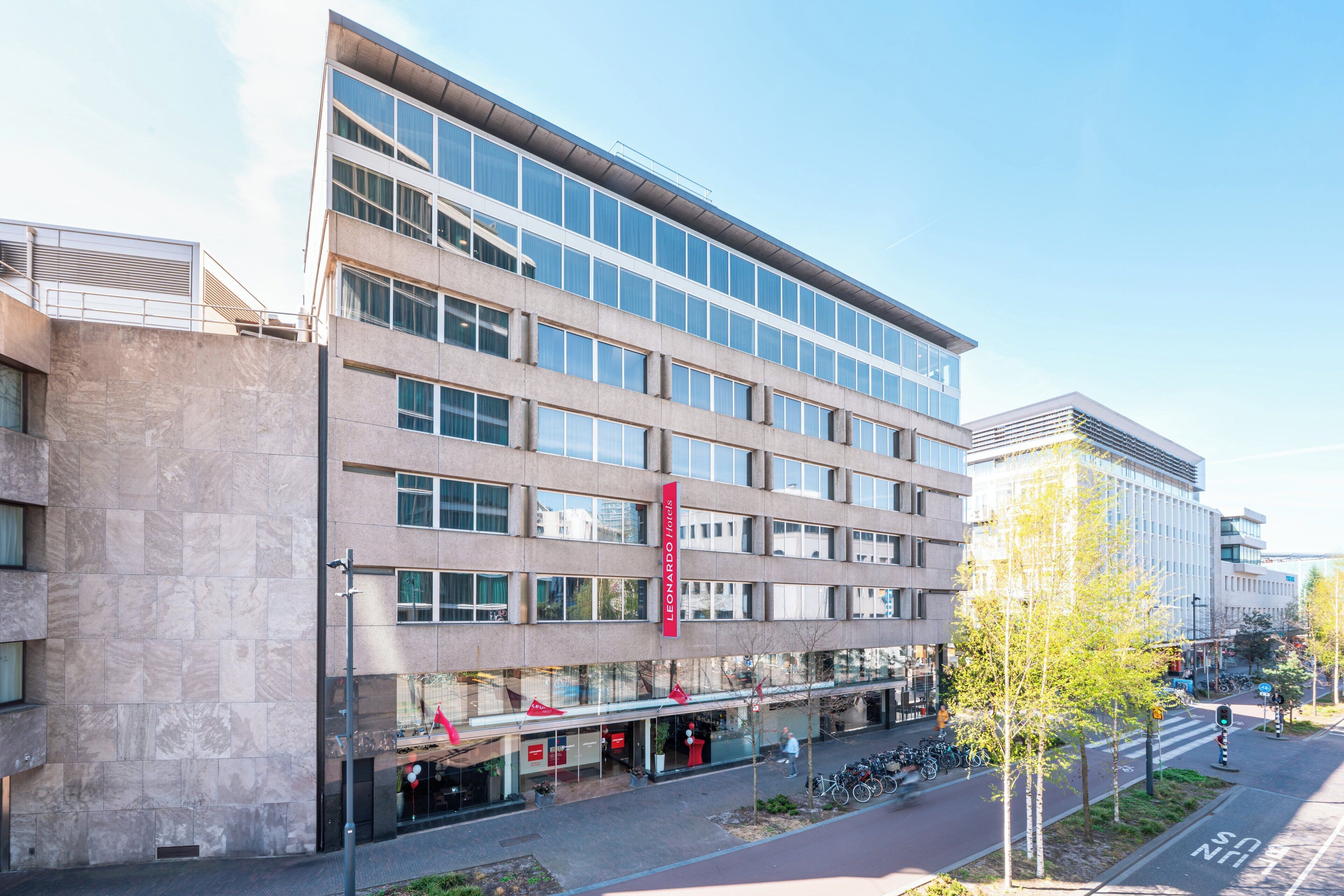 A multi-story building with a modern architectural design, featuring large windows and a prominent red sign.
