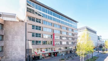 Un immeuble à plusieurs étages doté d’une architecture moderne, caractérisé par de grandes fenêtres et une enseigne rouge bien visible.