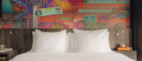 A bed with white linens, a wooden headboard, and a nightstand with a cup and books.