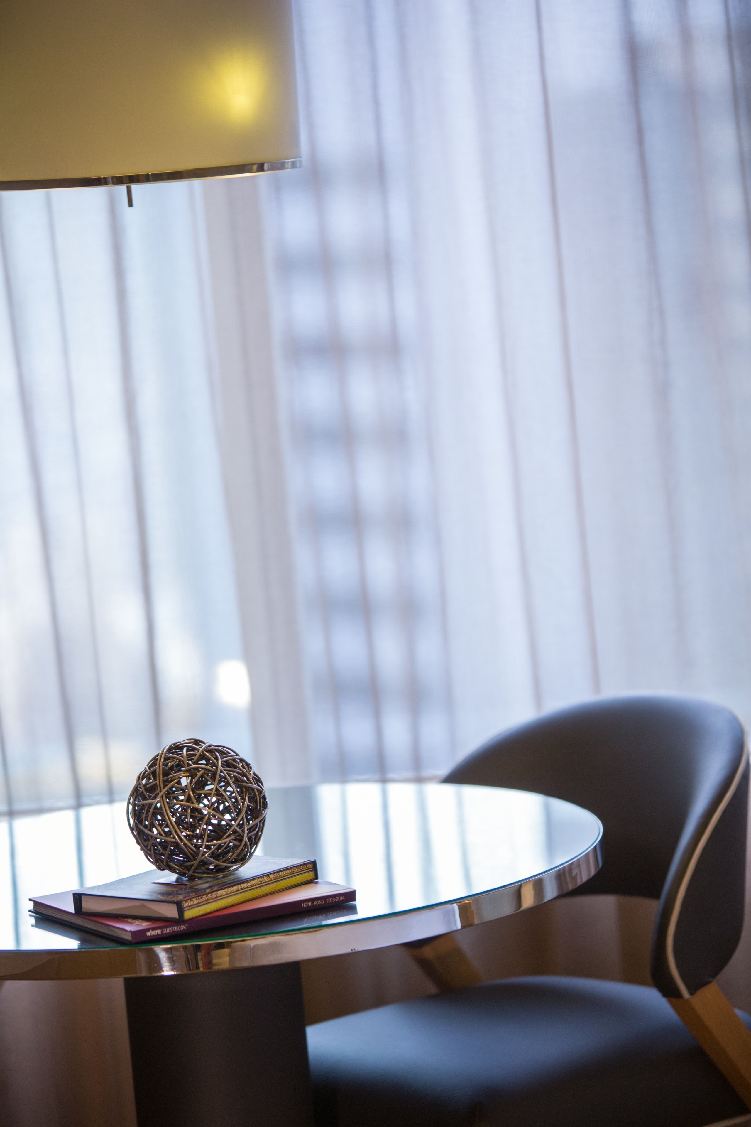 Una habitación moderna con una mesa redonda de vidrio, una silla negra y un objeto esférico decorativo sobre la mesa.