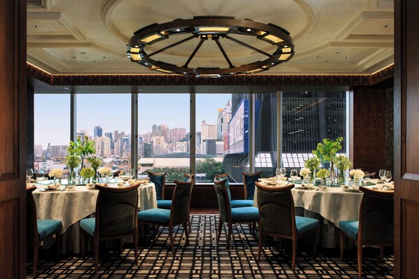 A restaurant with tables set for dining, large windows offering a city view, and a patterned floor. - Renaissance Harbour View Hotel Hong Kong (Hong Kong)