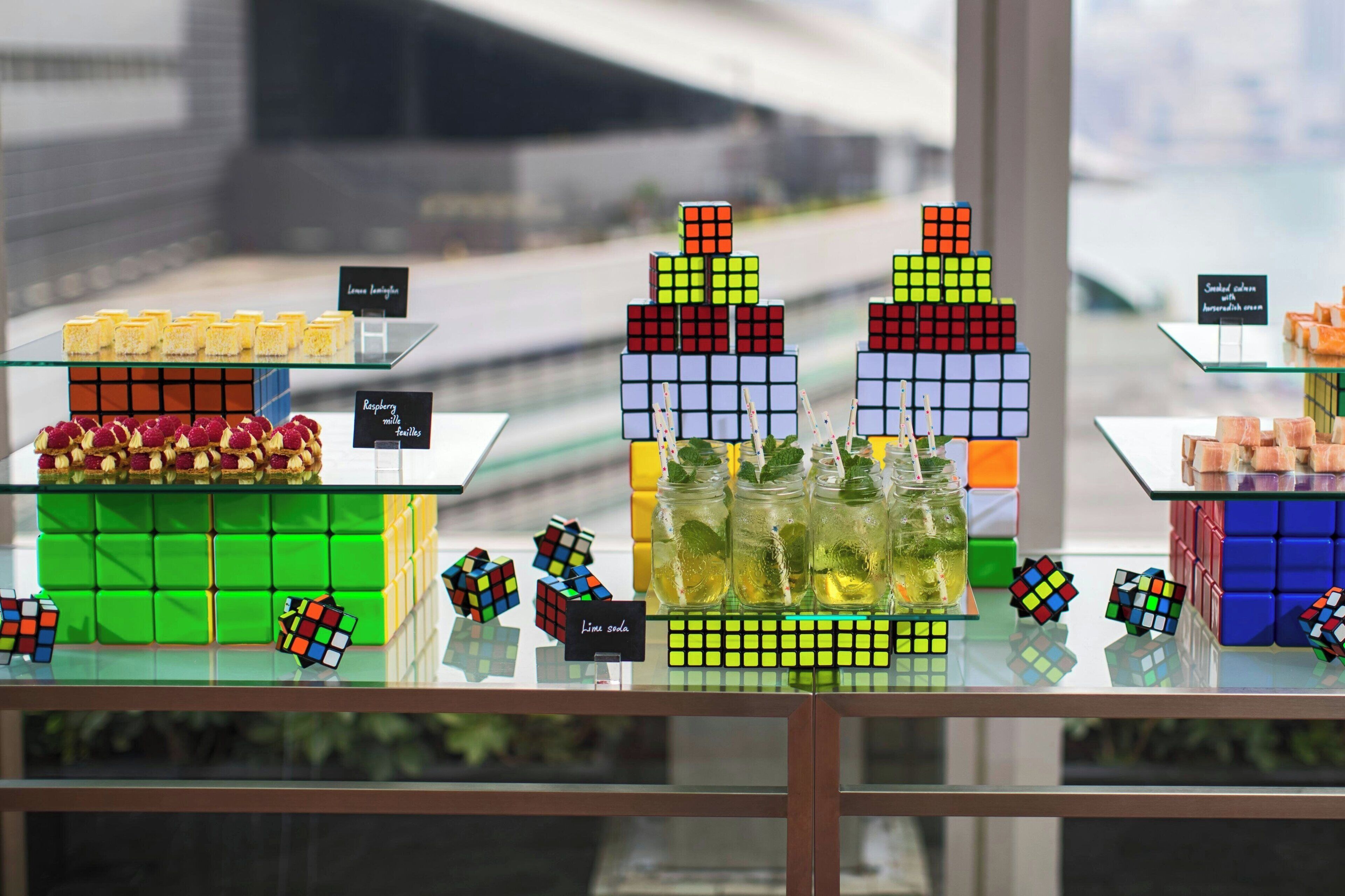 En uppvisning av färgglada Rubiks kuber och glasburkar med lemonad på en glasskiva.